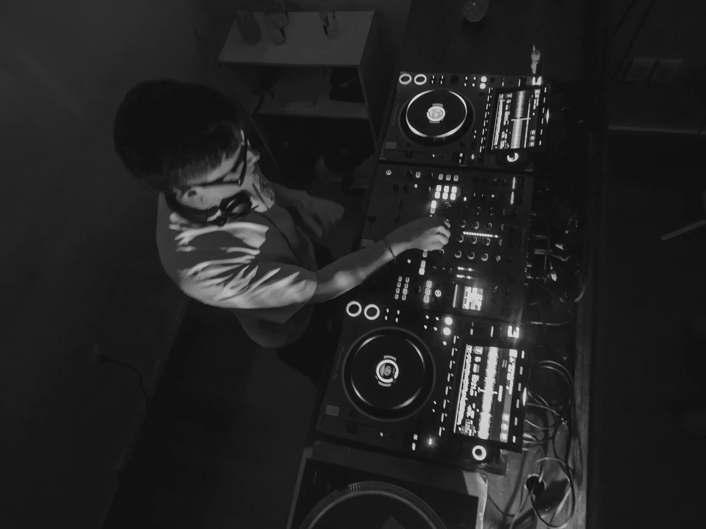 Black and white close-up of DJ equipment in a dark booth